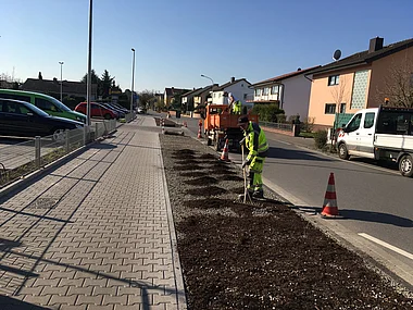 Straßenbauarbeiter ebnen Asphalt auf einer Wohnstraße.